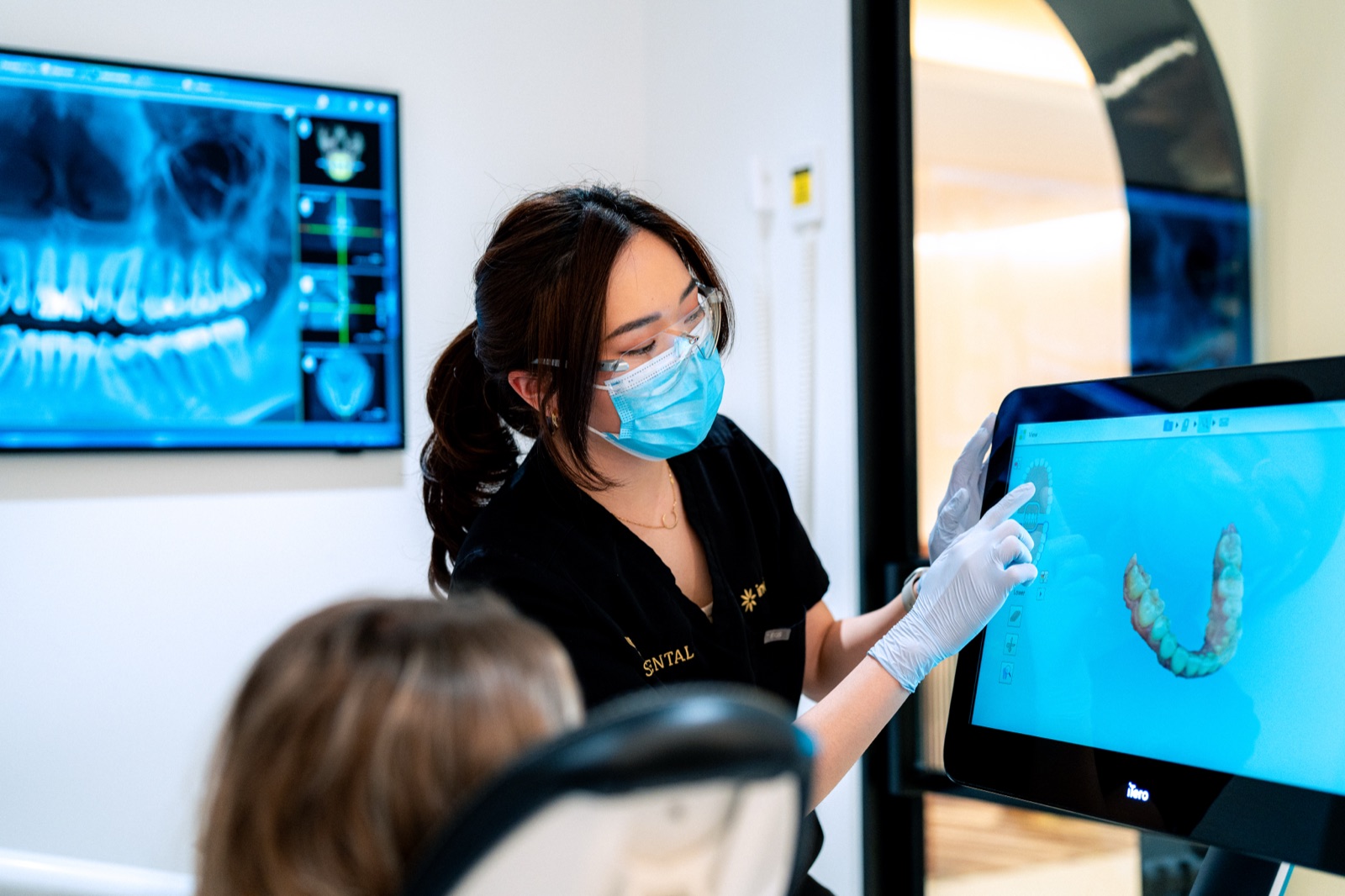 A clinician reviewing digital X-rays on screen with a patient
