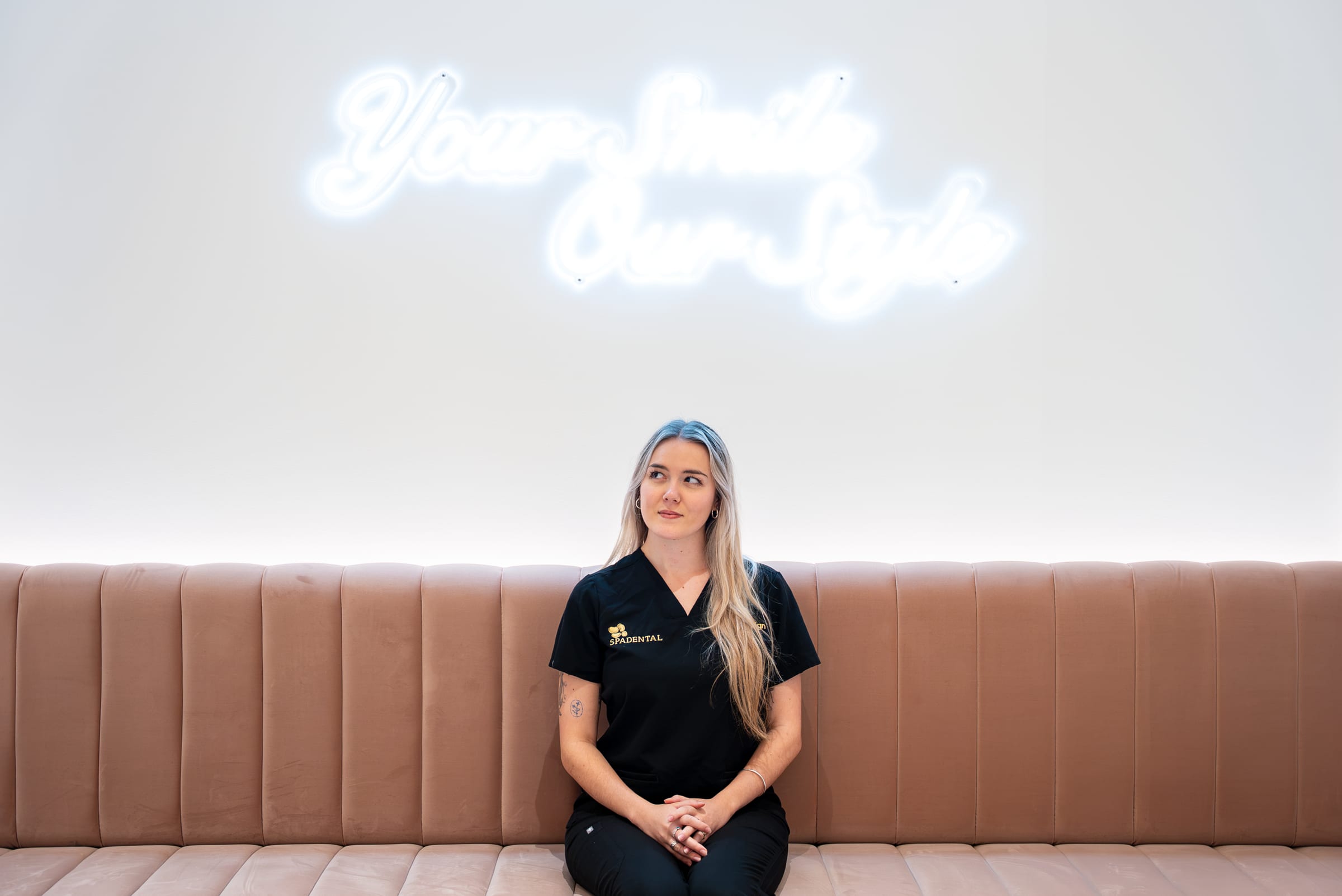 A Spa Dental clinician in the practice lounge beneath the neon sign